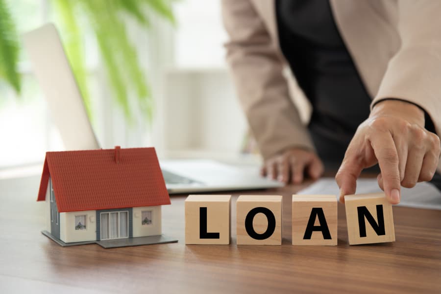 Wooden blocks spelling out word loan situated next to model home